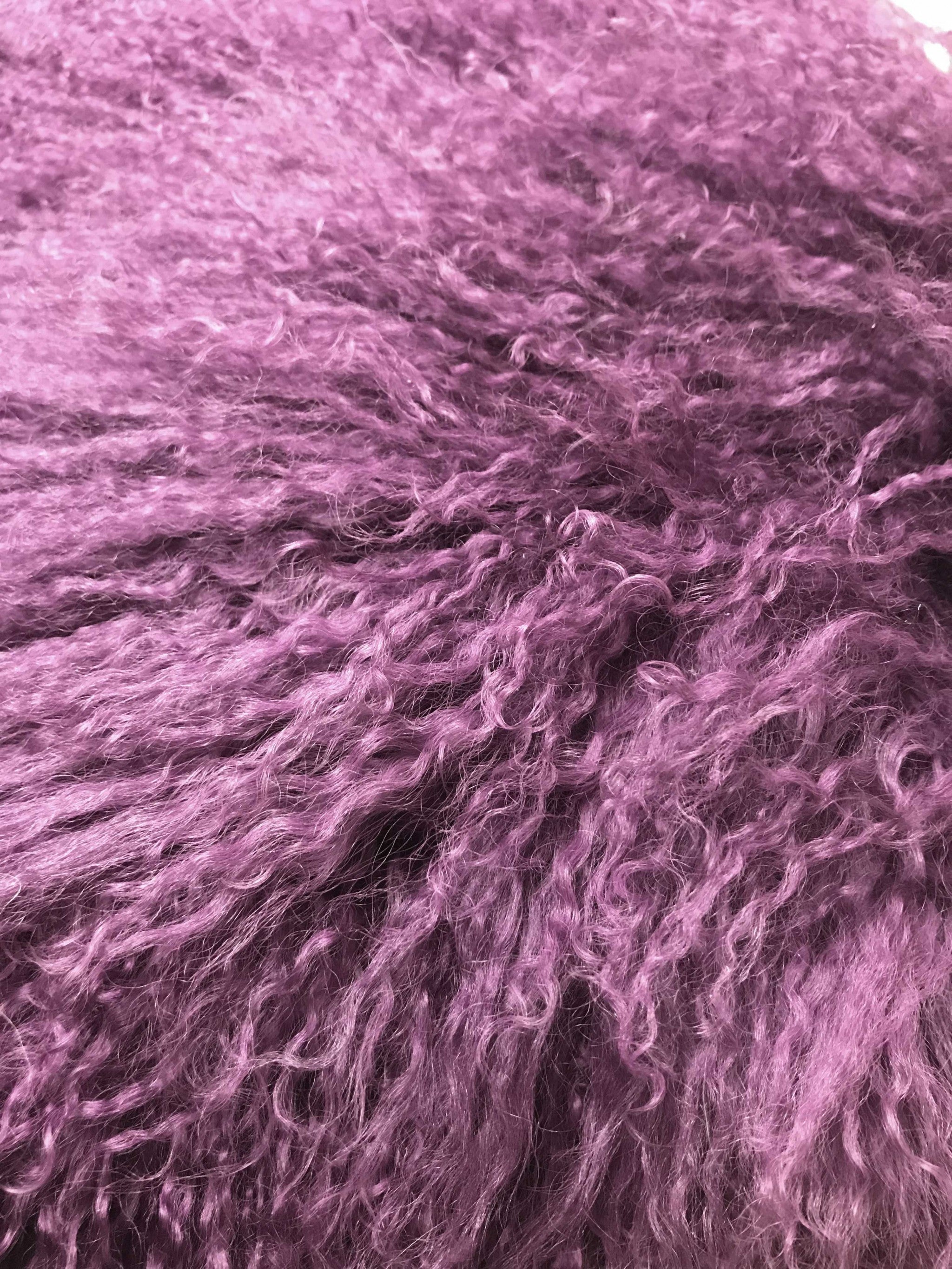 A luxurious 17-inch purple genuine Tibetan lamb fur pillow with a soft microsuede backing, elegantly displayed on a sofa.