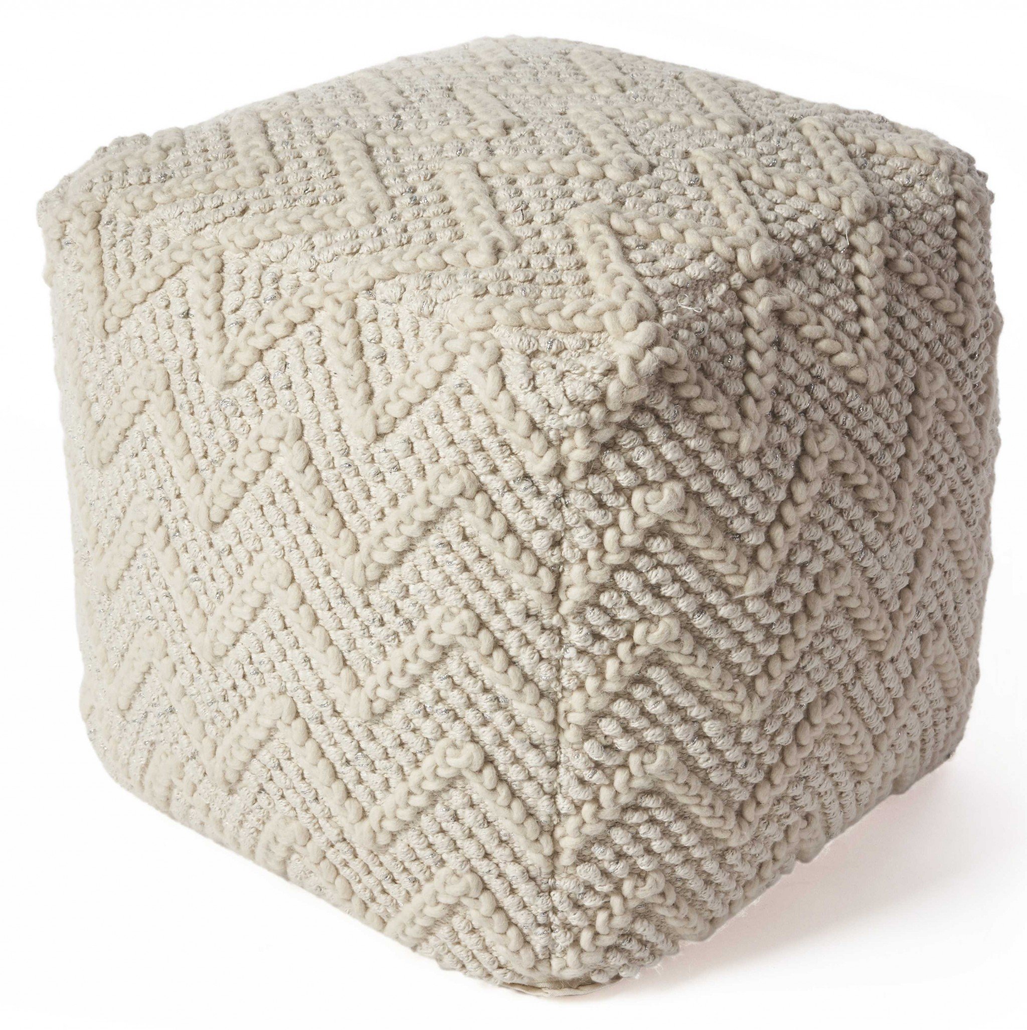 A stylish 18" x 18" wool ivory pouf, handmade with a blend of wool, cotton, and silver lurex threads, perfect for contemporary home decor.
