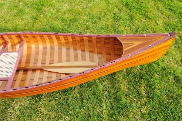 Handcrafted wooden canoe with ribs and curved bow, showcasing clear graded cedar and fiberglass epoxy finish.