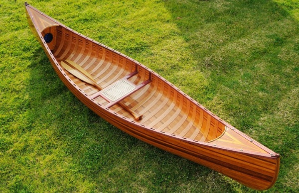 Handcrafted wooden canoe with ribs and curved bow, showcasing clear graded cedar and fiberglass epoxy finish.