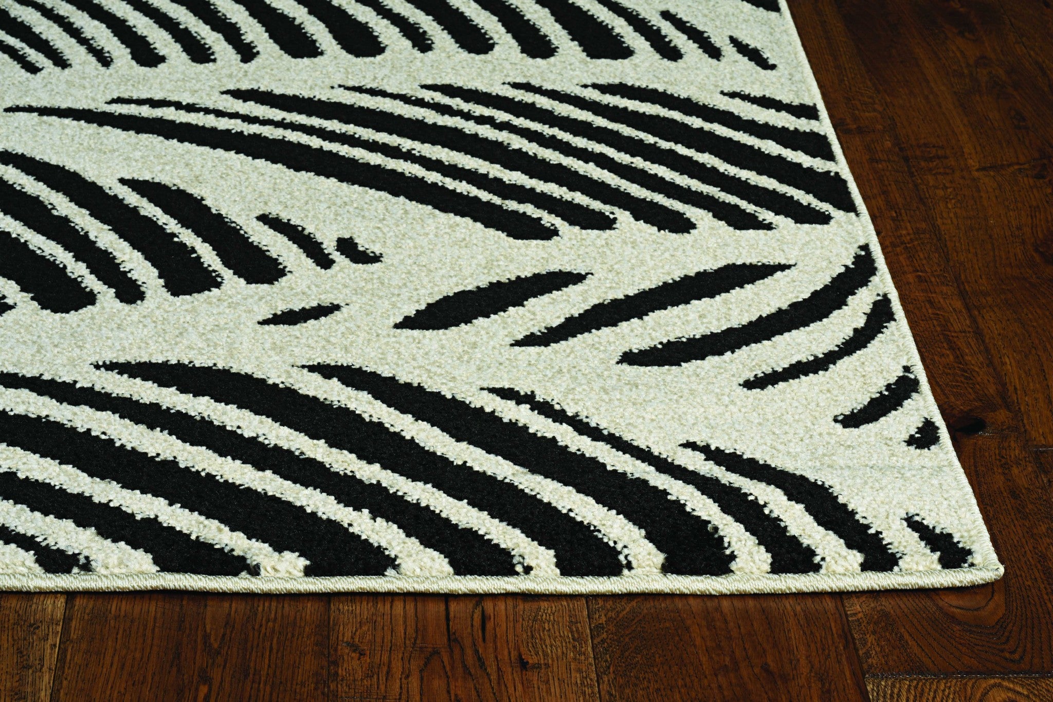 A stylish black and white machine-woven rug featuring a tropical palm design, perfect for indoor and outdoor use.