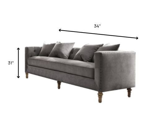 Gray velvet upholstery sofa with tufted back and 4 pillows, showcasing mid-century modern design and elegant nailhead trim.