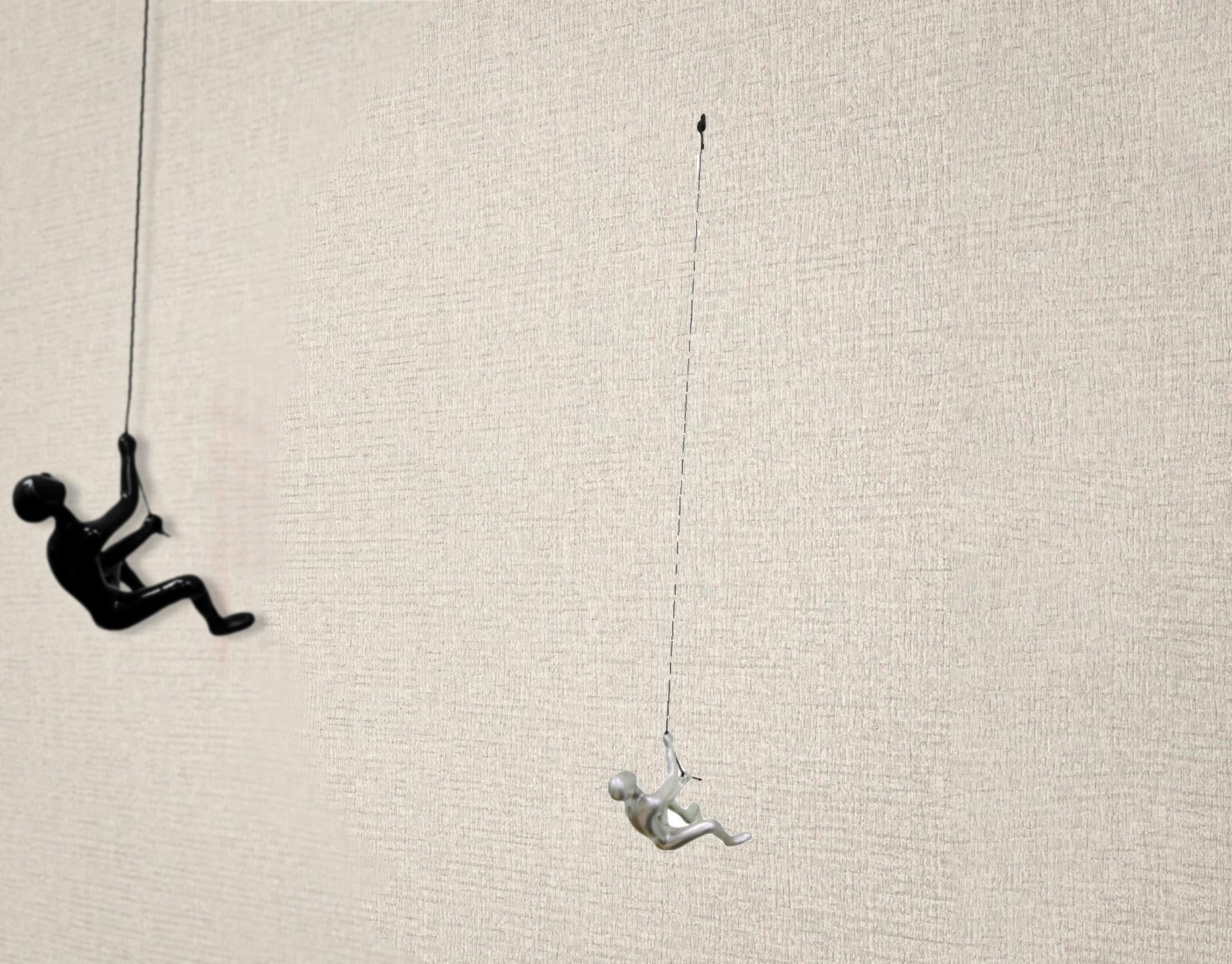 Silver climbing man wall art sculpture, elegantly designed with a twisted rope for hanging, perfect for modern decor.