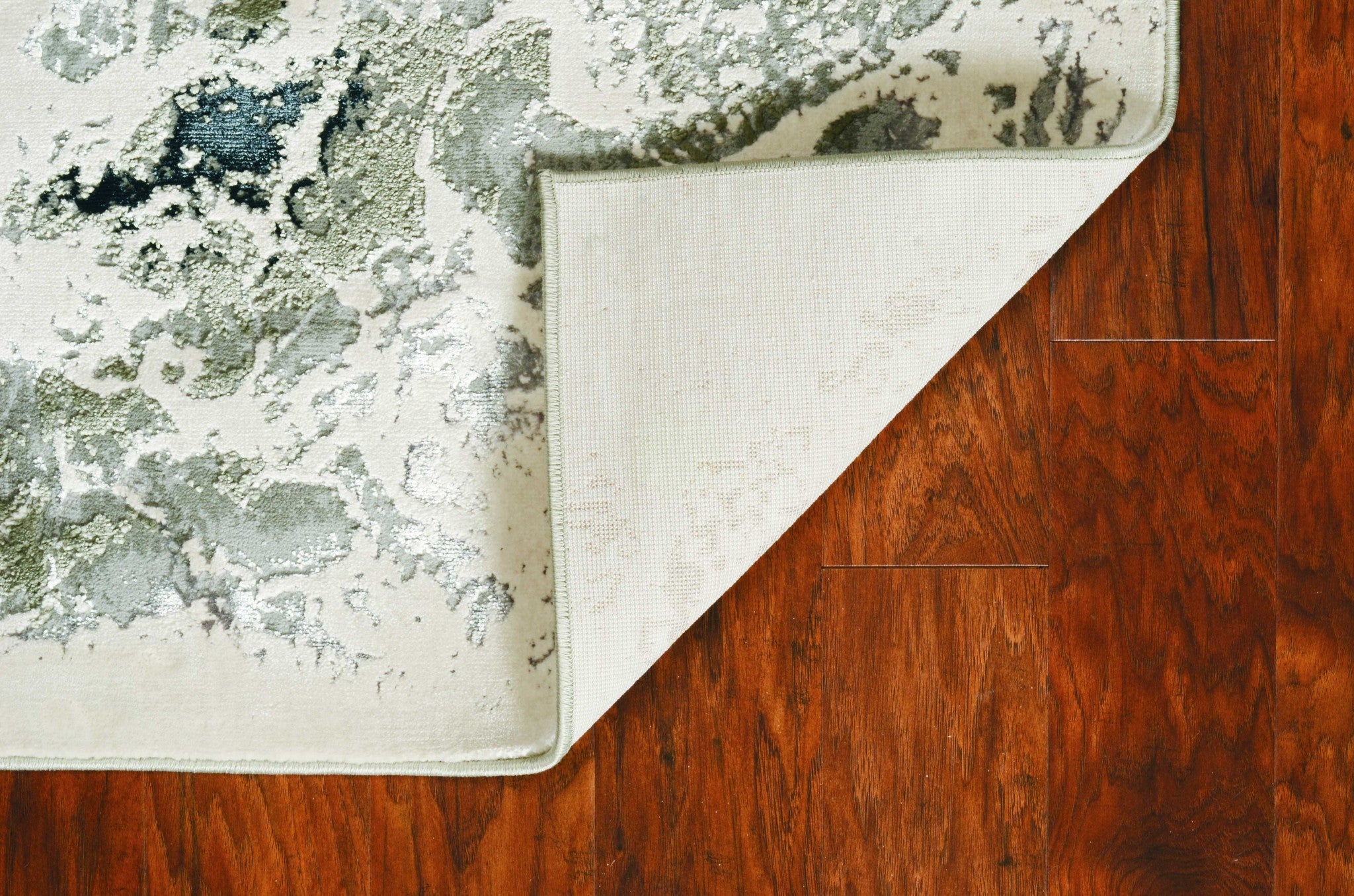 A stylish silver machine woven abstract watercolor indoor area rug, showcasing a modern design with paint-dripping effects and layered patterns.