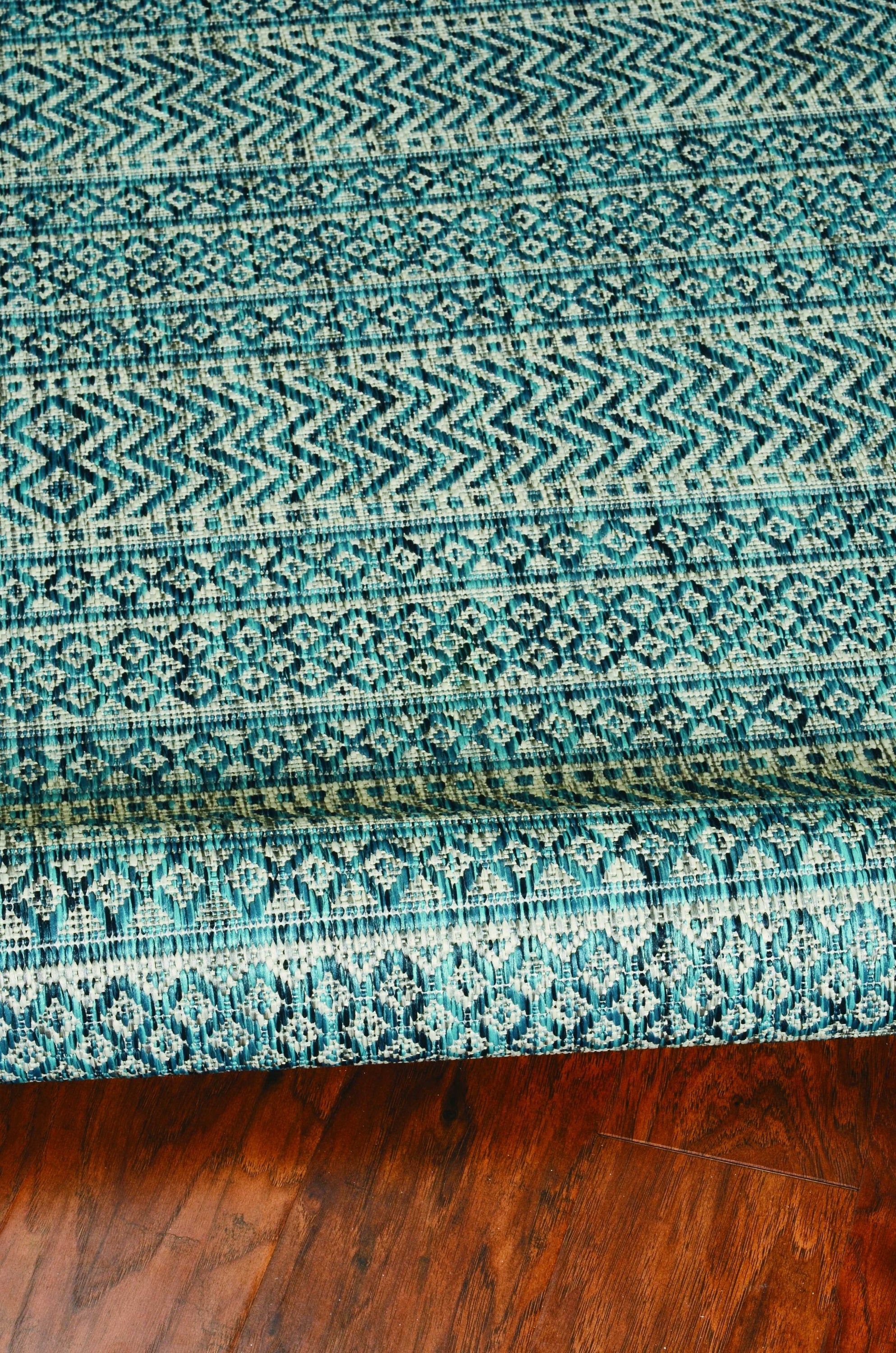 Teal tribal indoor outdoor rug, machine woven, UV treated, showcasing vibrant colors and patterns, perfect for enhancing any space.