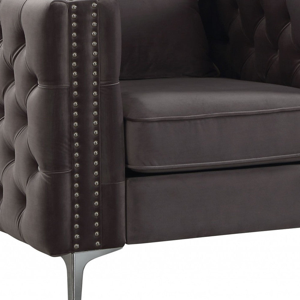 A stylish dark gray velvet chair with button tufted design and an accent pillow, resting on chrome metal bracket legs.