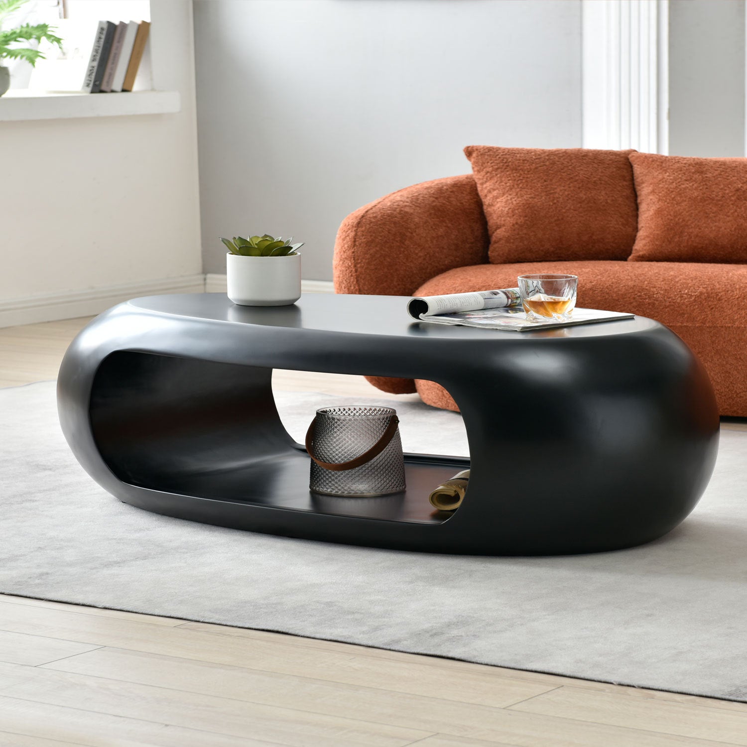 A modern oval coffee table made of sturdy fiberglass, featuring a sleek black finish, perfect for contemporary living spaces.