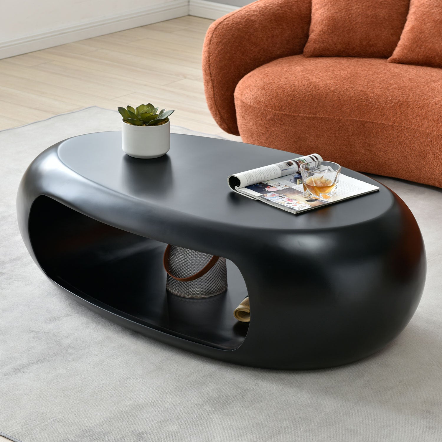 A modern oval coffee table made of sturdy fiberglass, featuring a sleek black finish, perfect for contemporary living spaces.