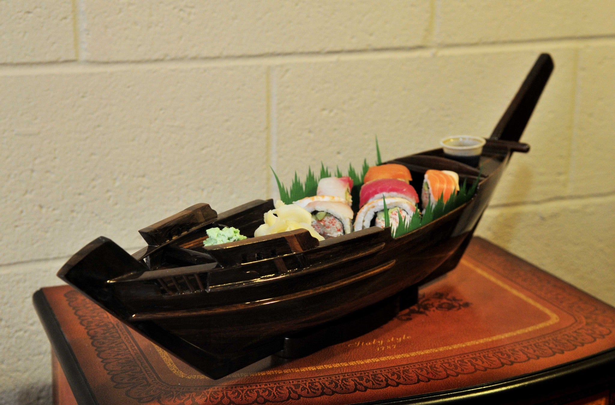 A beautifully crafted wooden sushi tray designed as a dhow boat, showcasing its unique shape and elegant finish.