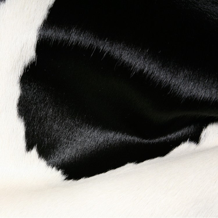 Handmade black and white cowhide area rug measuring 60x84 inches, showcasing a luxurious texture and unique patterns.