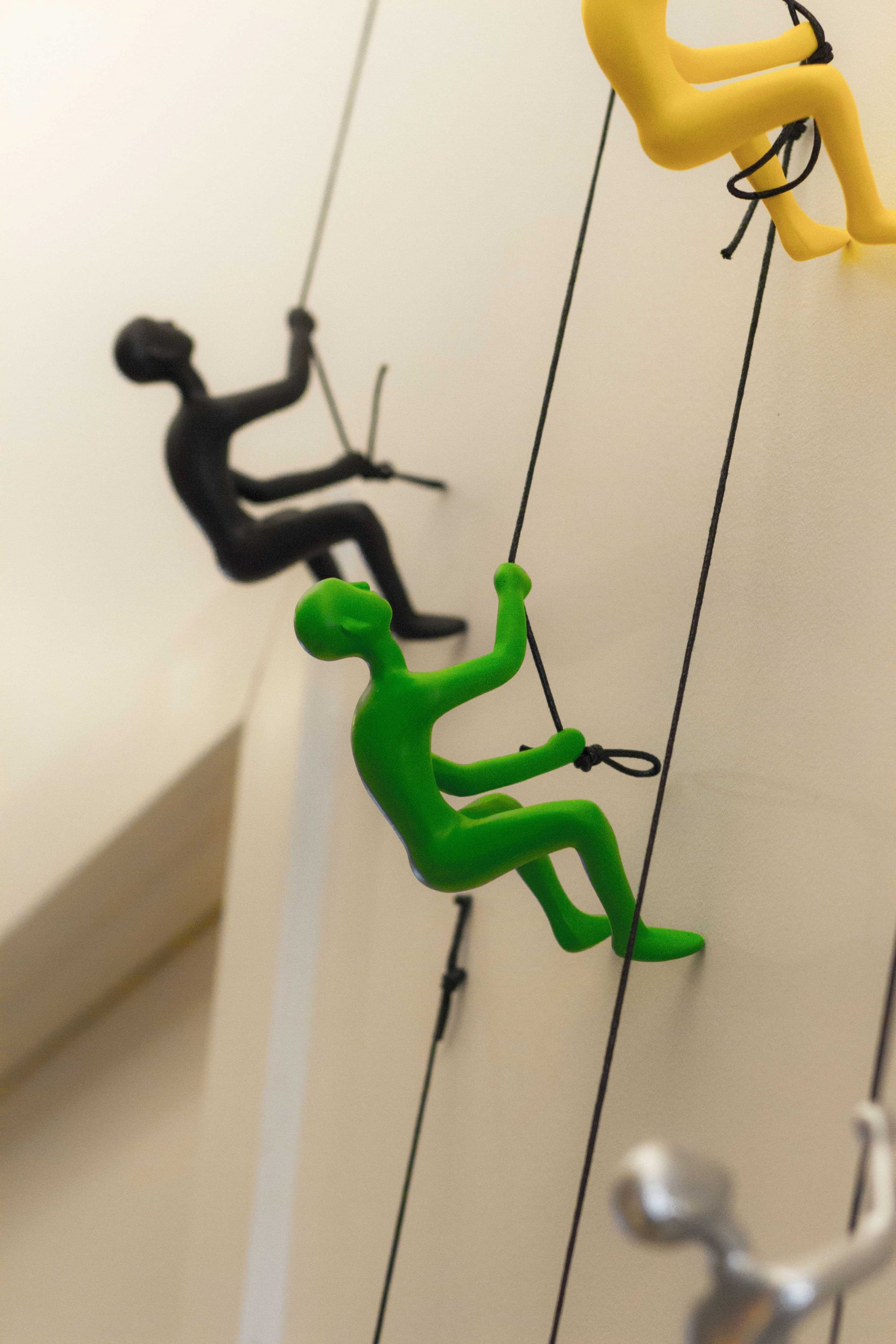A striking green resin sculpture of a man climbing, designed for wall art, showcasing a modern aesthetic.