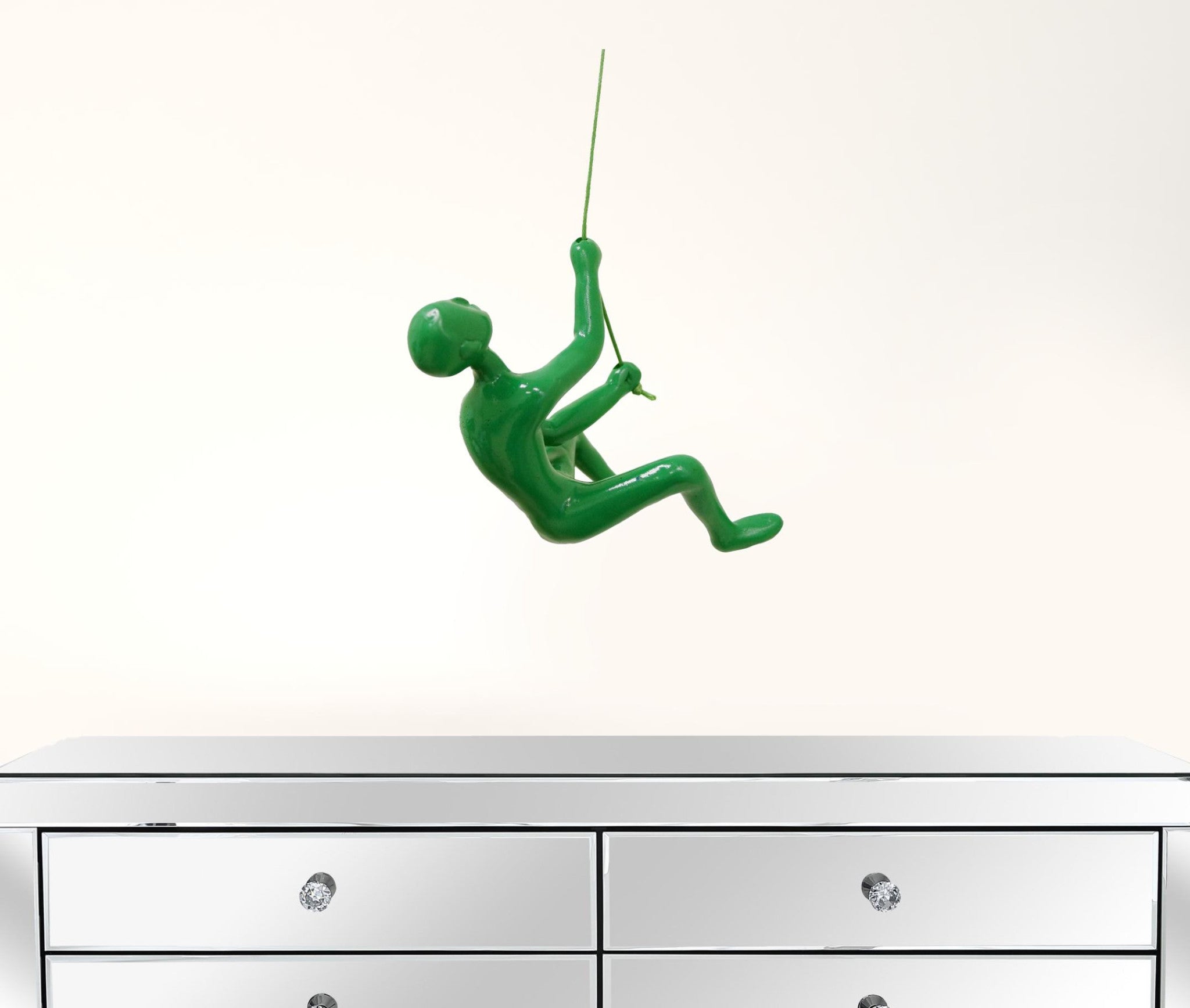 A striking green resin sculpture of a man climbing, designed for wall art, showcasing a modern aesthetic.