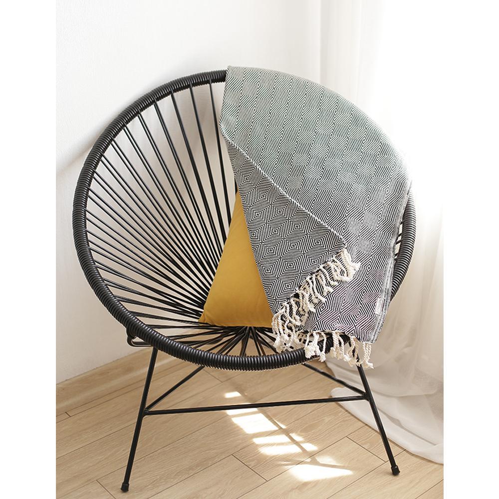 A luxurious 70-inch black geometric handwoven throw blanket displayed elegantly on a couch, showcasing its intricate design and soft texture.