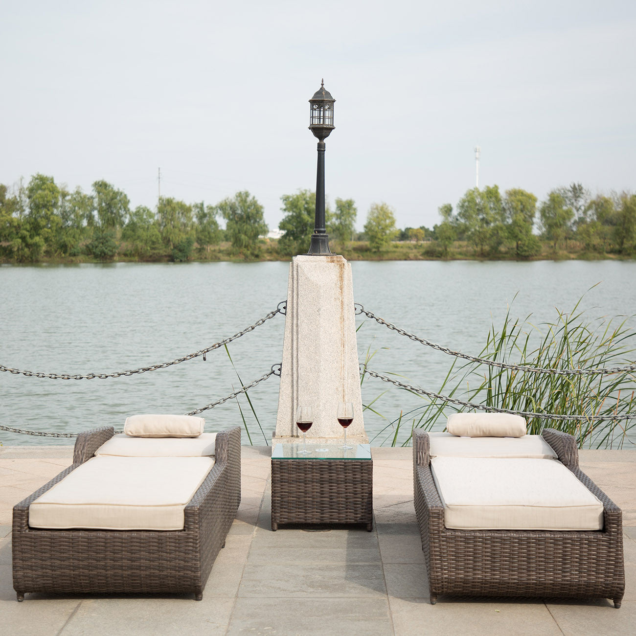 Brown 3-Piece Outdoor Arm Chaise Lounge set featuring two lounges with cushions and a glass-top table, perfect for outdoor relaxation.