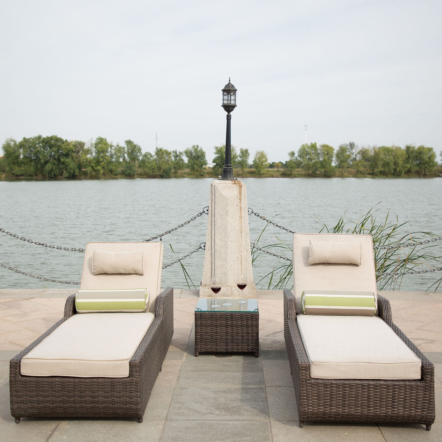 Brown 3-Piece Outdoor Arm Chaise Lounge set featuring two lounges with cushions and a glass-top table, perfect for outdoor relaxation.