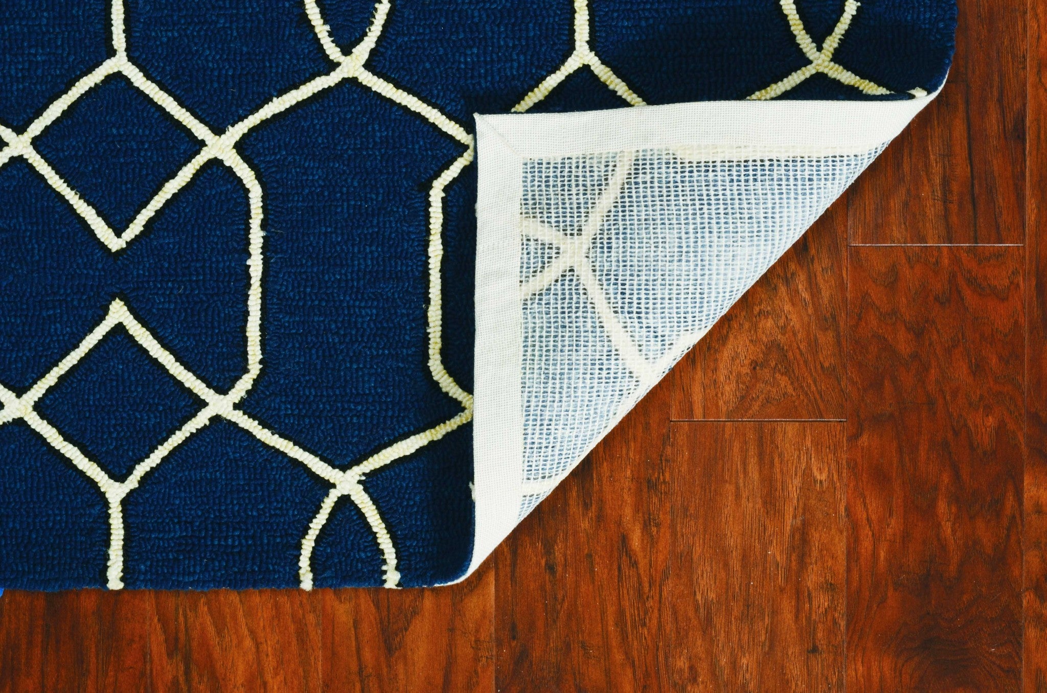 A beautiful navy blue hand-hooked rug featuring a trellis design, perfect for indoor and outdoor use, showcasing intricate patterns.