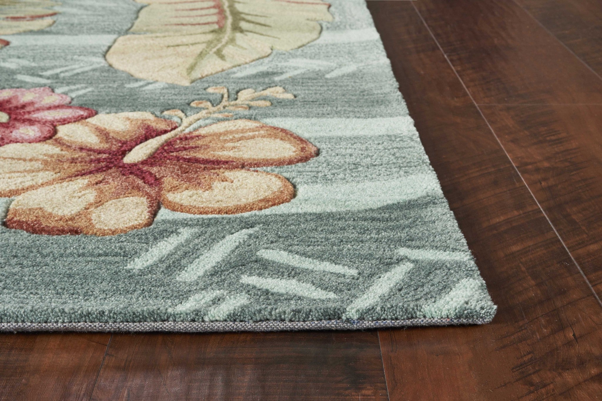 A vibrant seafoam green machine woven rug featuring tropical plant designs, perfect for indoor living spaces.