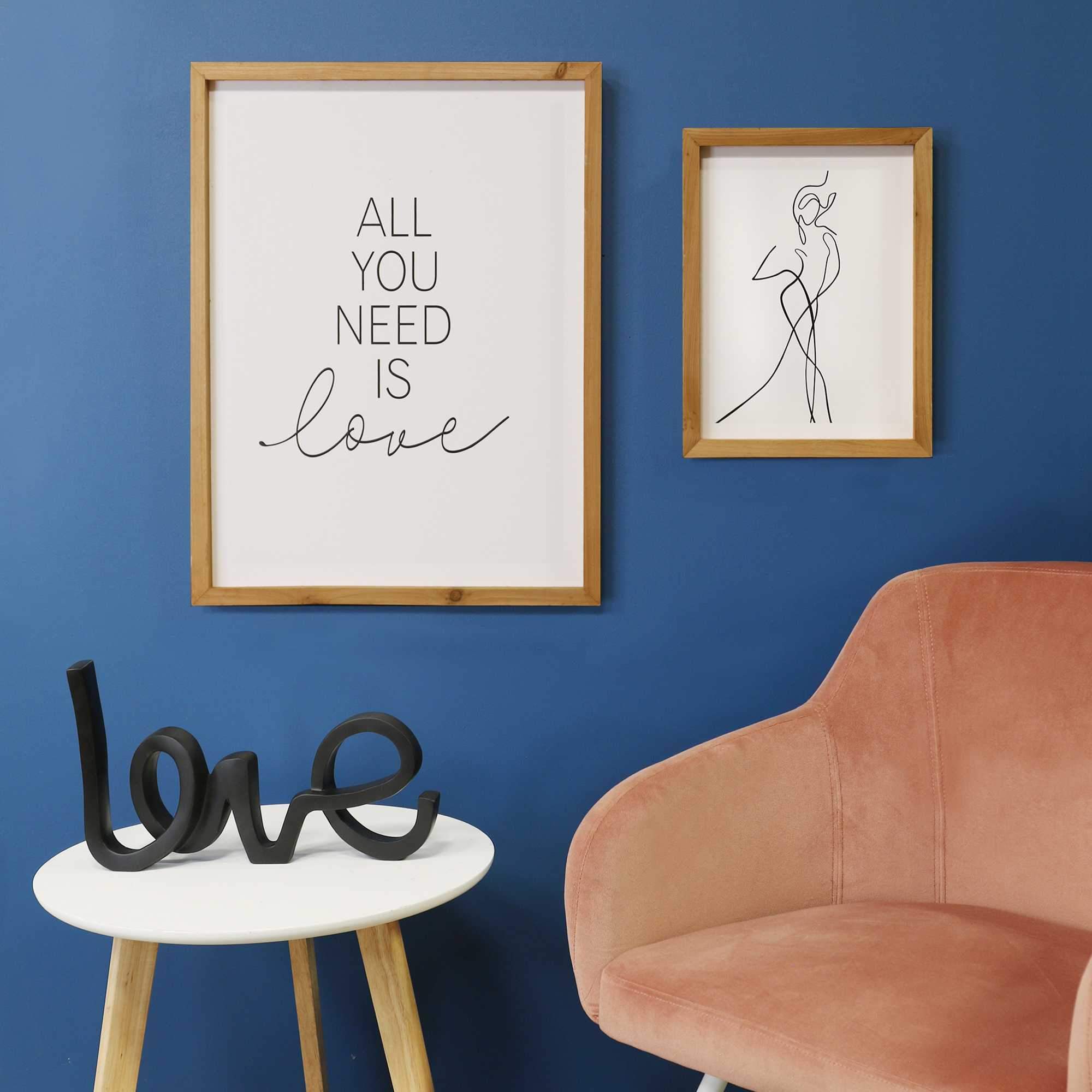 Framed wall art featuring the quote 'All You Need is Love' in black-and-white, set in a natural wood frame.