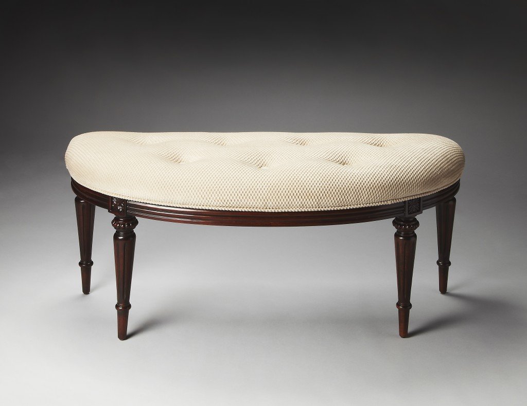 Crescent shape ivory tufted bench with carved cherry finish legs, showcasing elegant design and luxurious upholstery.