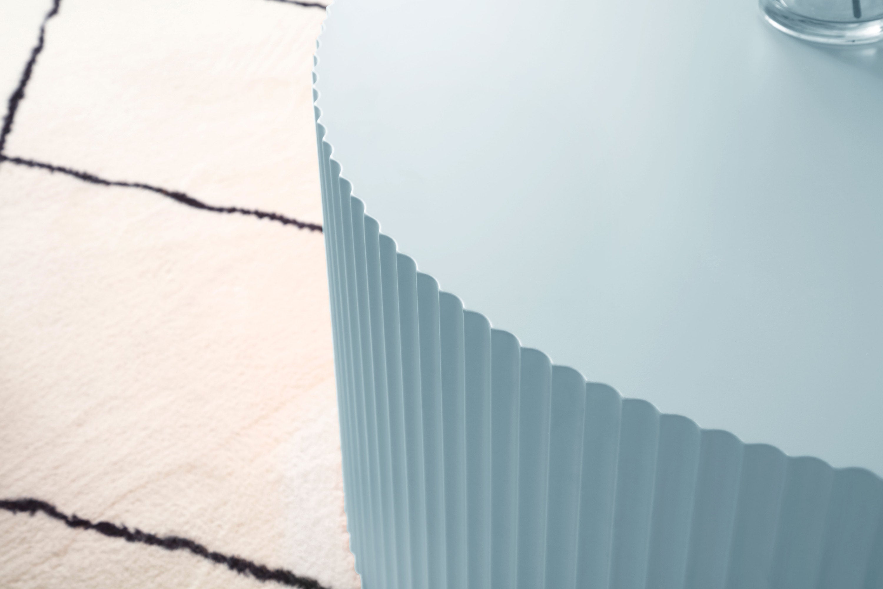 Handcrafted round coffee table in light blue with elegant relief detailing, showcasing its smooth finish and stylish design.