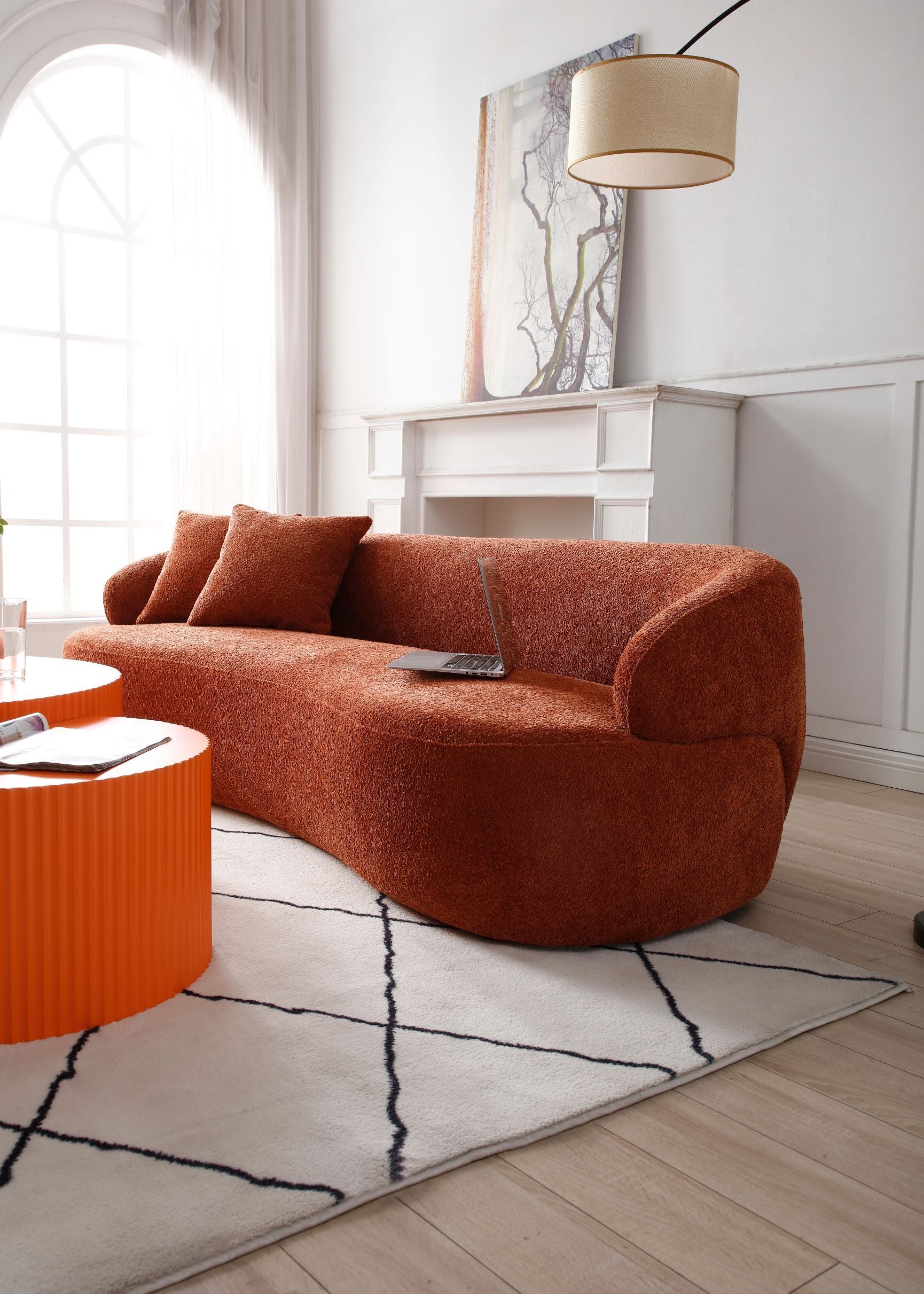 A stylish ORANGE Mid Century Modern Curved Sofa featuring a soft Boucle fabric, designed for comfort and elegance in a living room setting.