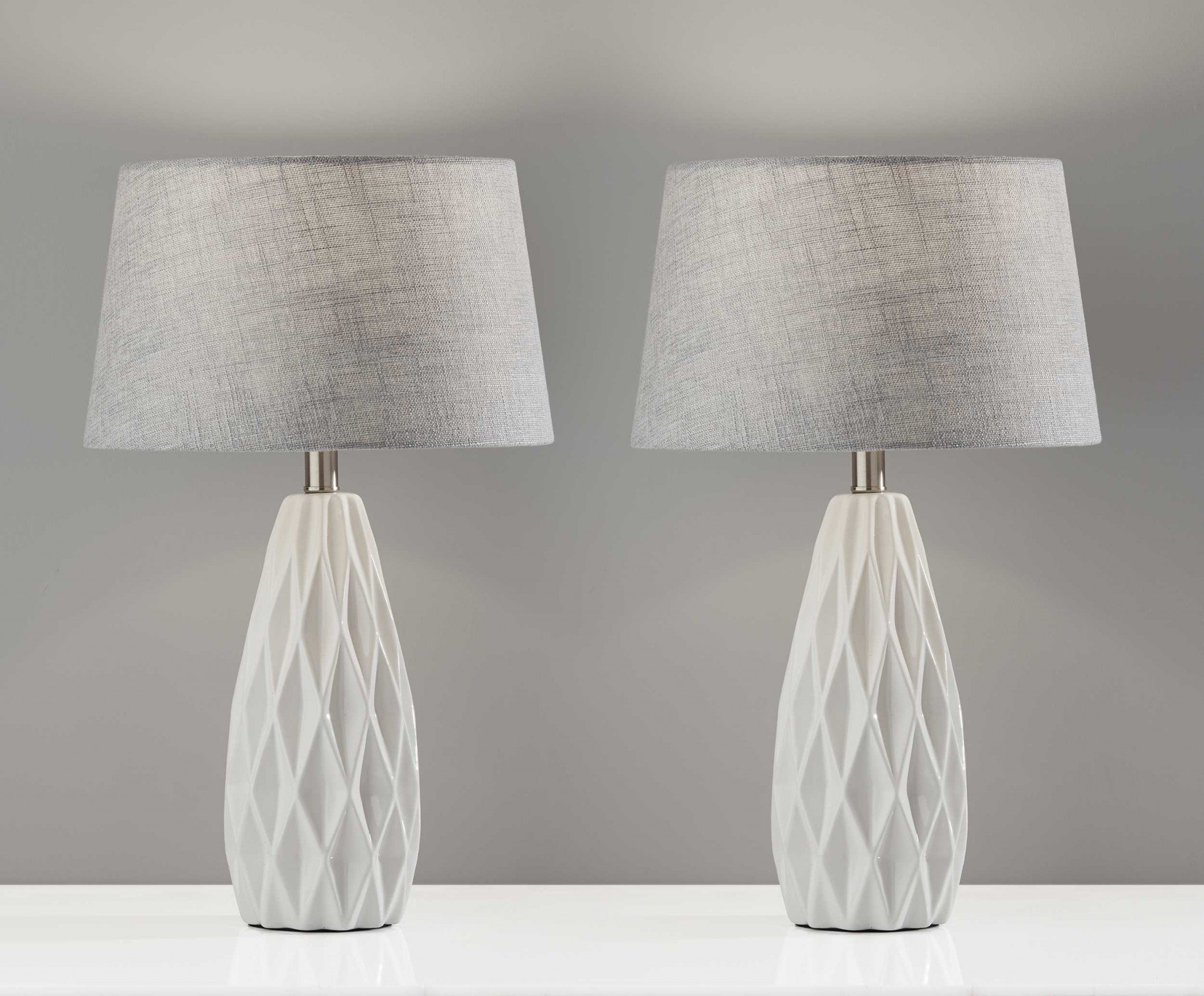 Set of 2 white ceramic table lamps with geometric bases and grey fabric shades, perfect for modern decor.