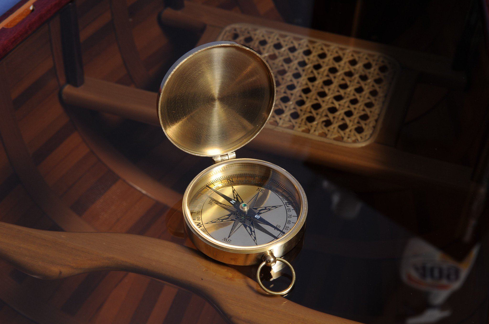 A shiny brass marine compass with a lid, showcasing its elegant design and craftsmanship, perfect for nautical decor.