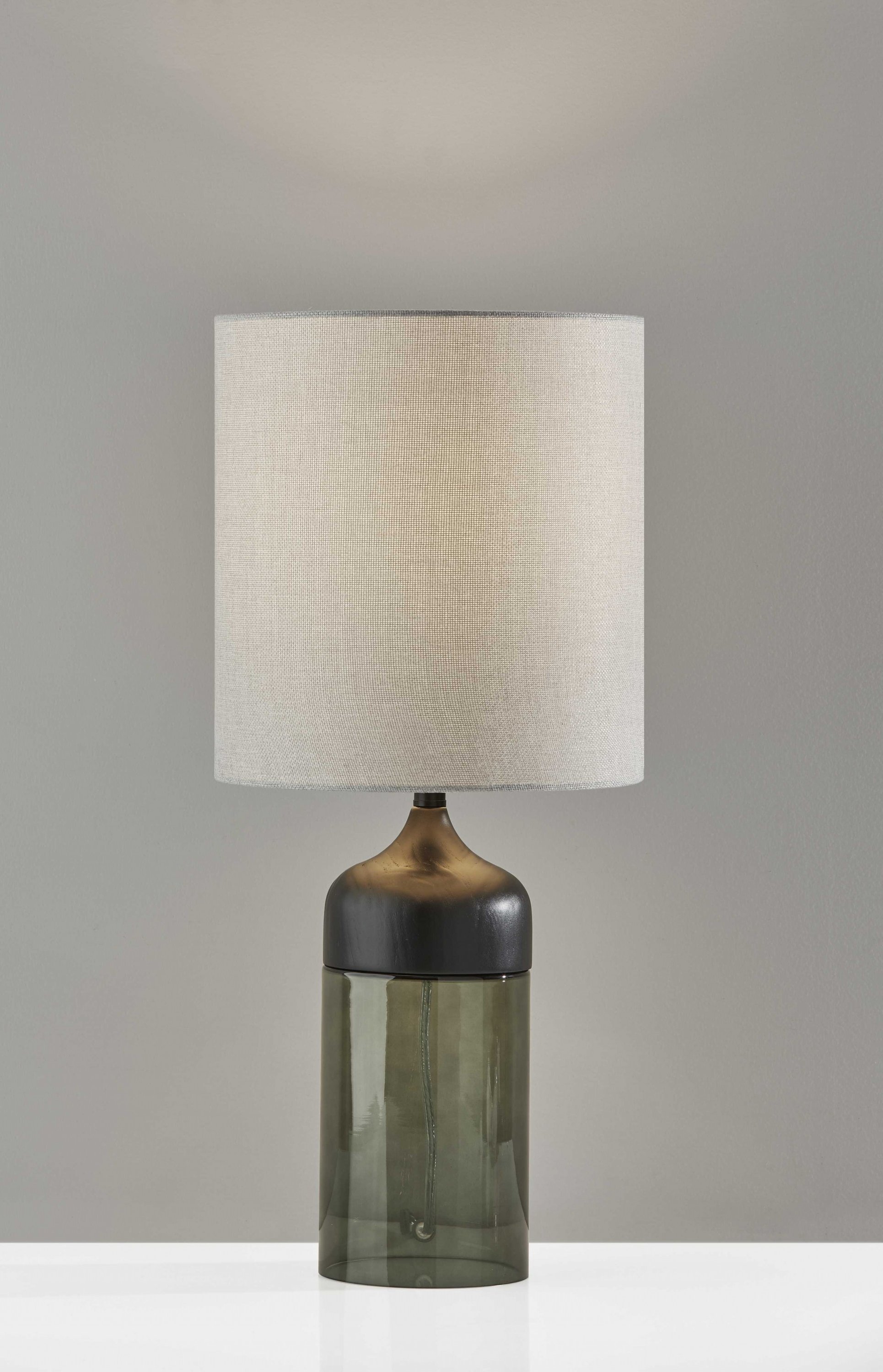 Tall table lamp featuring a black wood base and smoked glass accent with a lightly textured grey fabric shade.