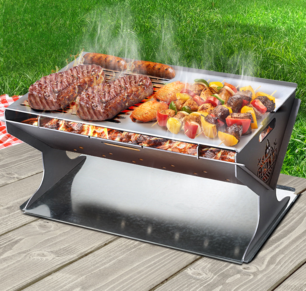 Grillz Fire Pit BBQ with stainless steel grill, portable and foldable design, set up for outdoor cooking.