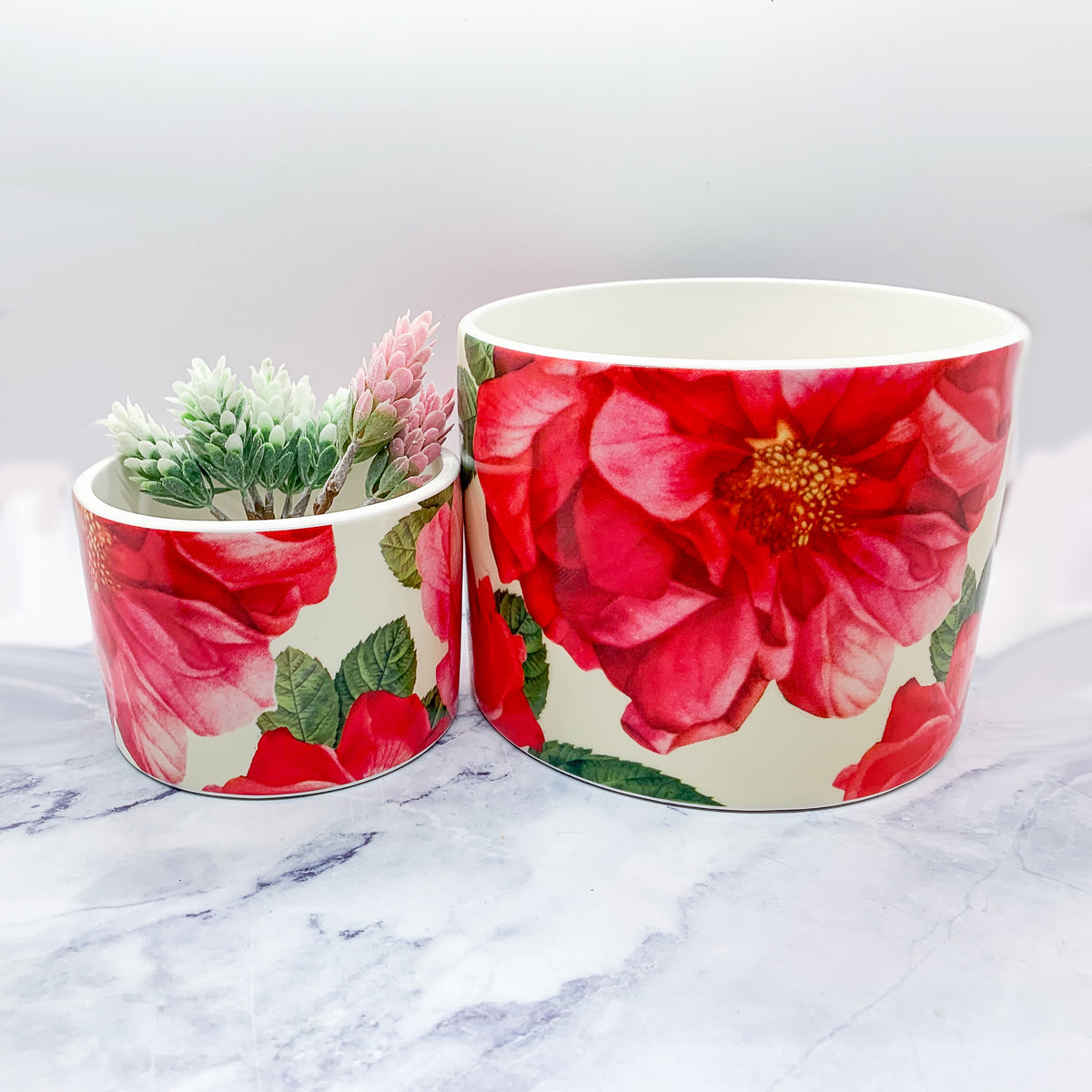 Two stunning Rose Marie floral cachepots in pink and red ceramic, showcasing intricate rose patterns.