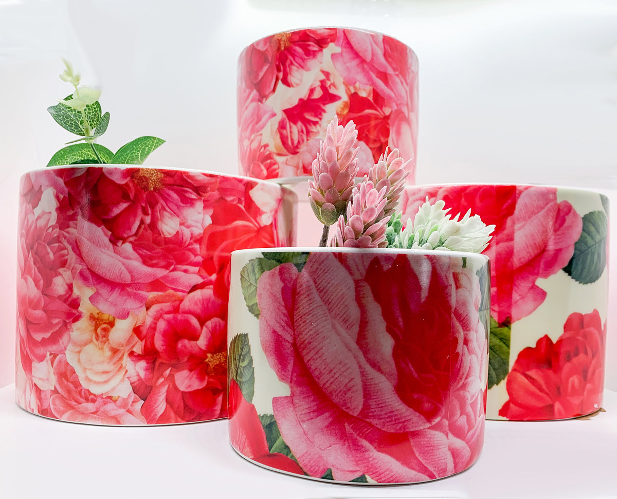 Two stunning Rose Marie floral cachepots in pink and red ceramic, showcasing intricate rose patterns.