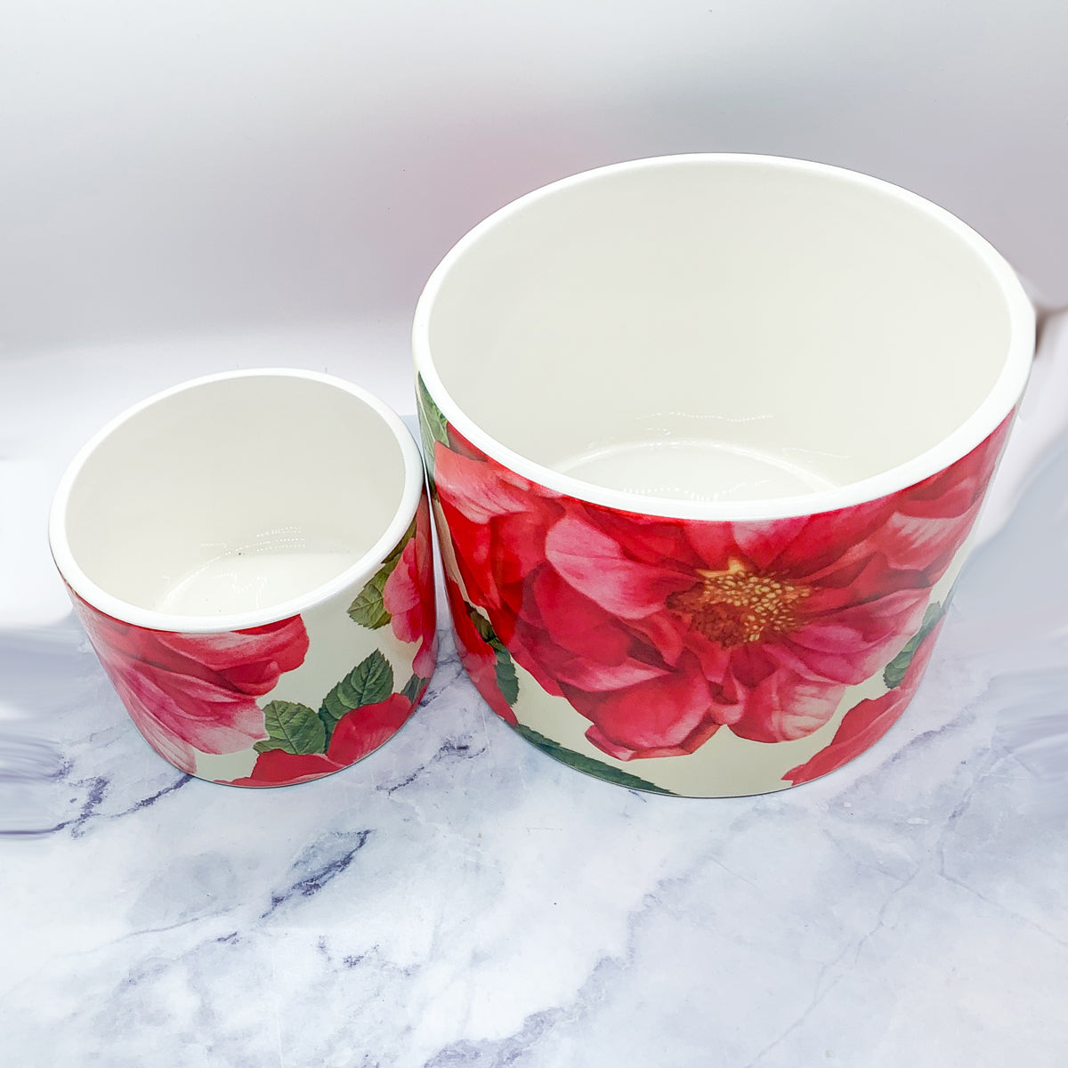 Two stunning Rose Marie floral cachepots in pink and red ceramic, showcasing intricate rose patterns.