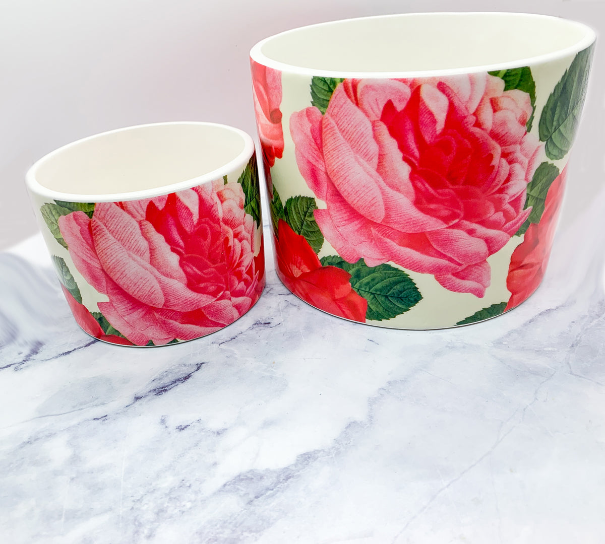 Two stunning Rose Marie floral cachepots in pink and red ceramic, showcasing intricate rose patterns.