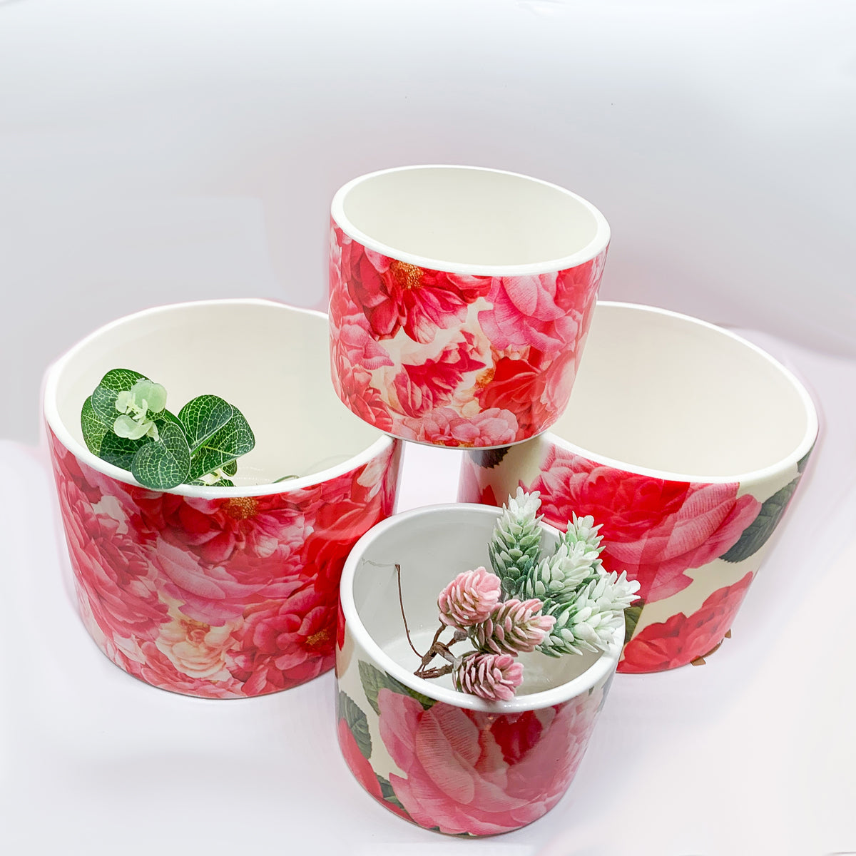 Two stunning Rose Marie floral cachepots in pink and red ceramic, showcasing intricate rose patterns.