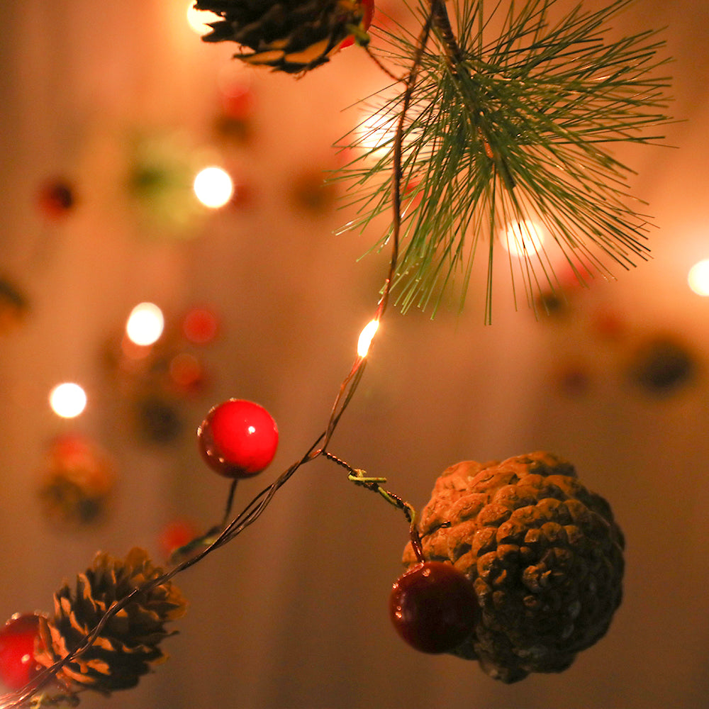 A beautifully arranged 6.56FT string of Christmas lights featuring pine cones, berries, and snowy leaves, glowing warmly with 20 LEDs.