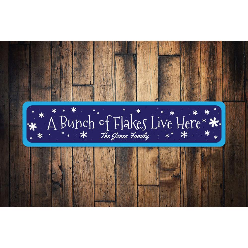 A decorative metal sign reading 'A Bunch of Flakes Live Here', featuring festive colors and design, perfect for Christmas decorations.
