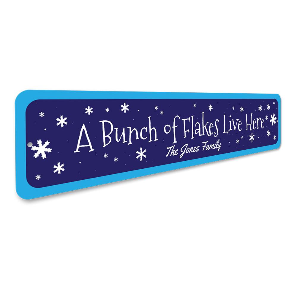 A decorative metal sign reading 'A Bunch of Flakes Live Here', featuring festive colors and design, perfect for Christmas decorations.