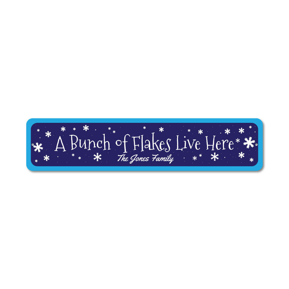 A decorative metal sign reading 'A Bunch of Flakes Live Here', featuring festive colors and design, perfect for Christmas decorations.