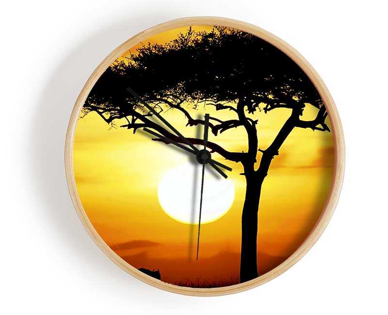 A stylish African Safari Tree clock made from natural bamboo, featuring a round face and clear Plexiglas lens, displayed in sunlight.
