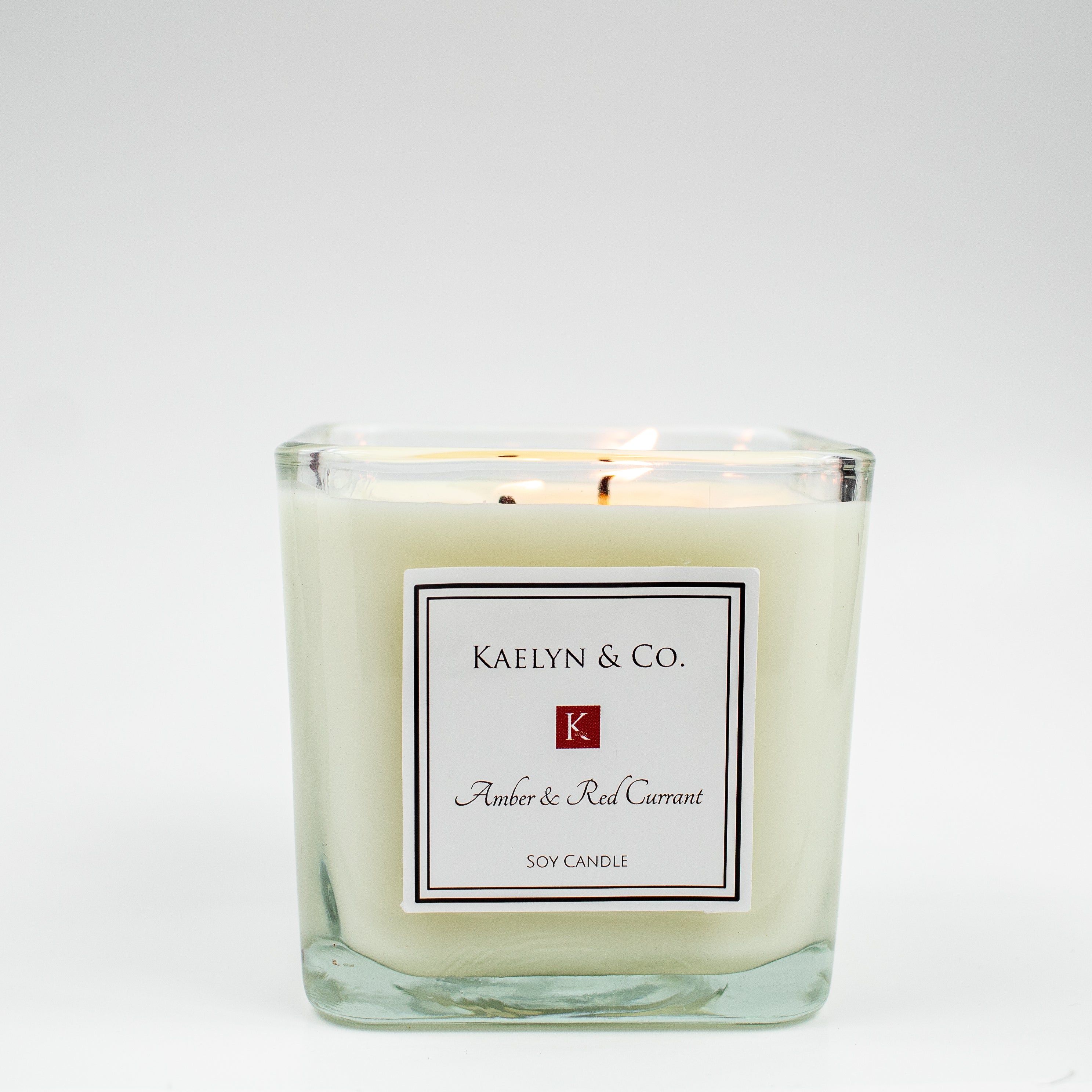 Amber & Red Currant Medium Cube Candle in elegant packaging, showcasing its rich color and double wick design.