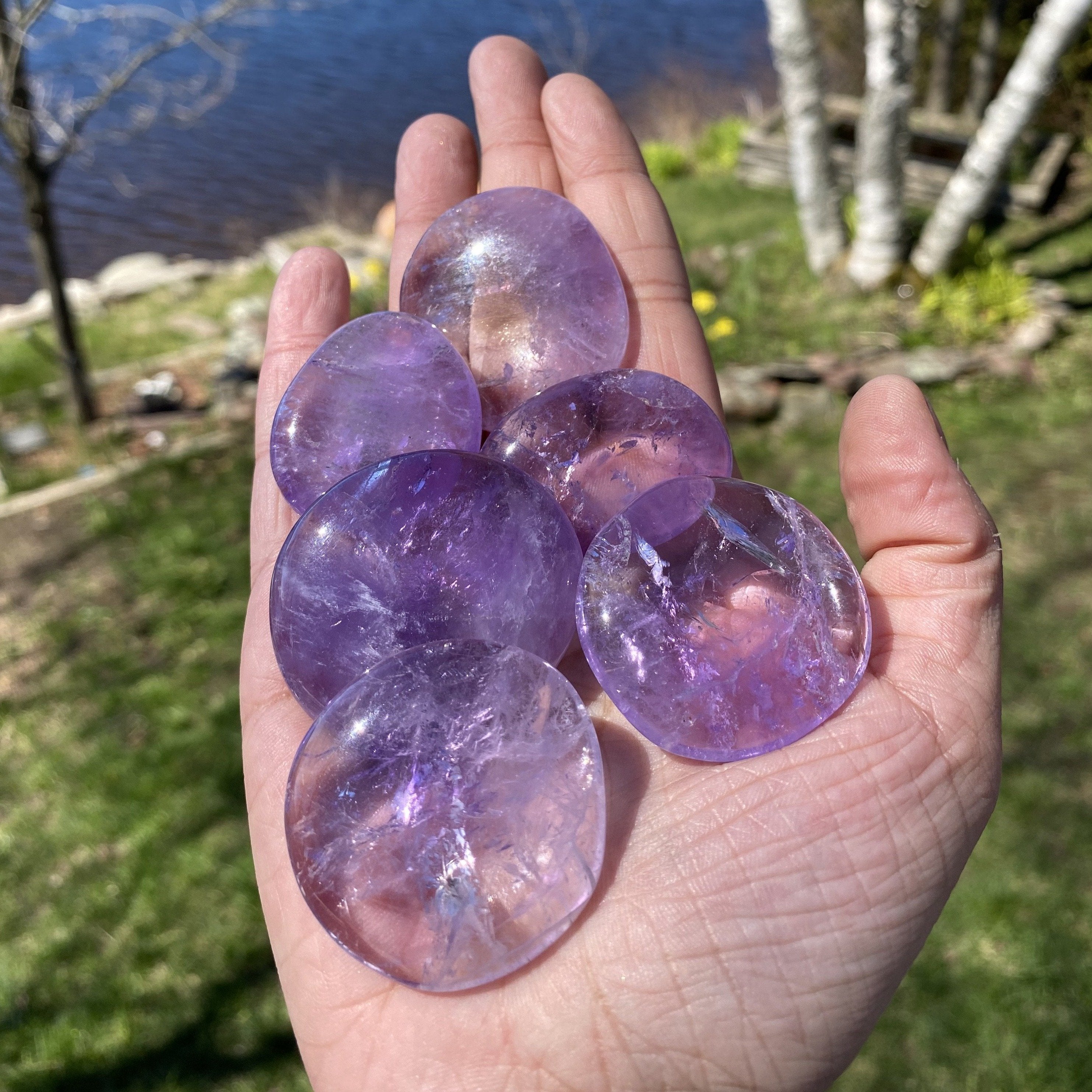 A collection of smooth, polished Amethyst Crystal Palm Stones showcasing their rich purple color and natural beauty.