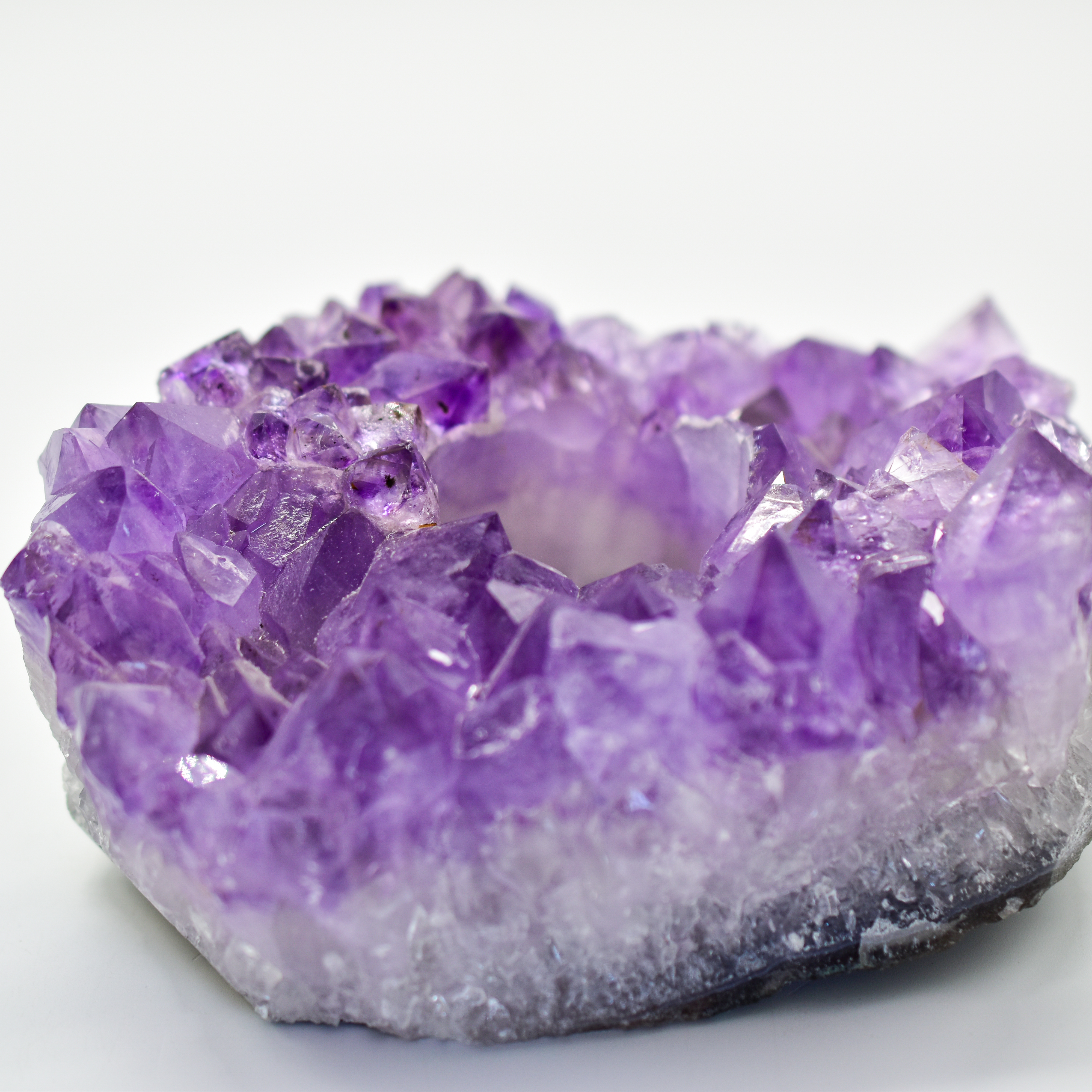 A large, natural Amethyst druzy crystal candle holder with unique colors and textures, designed for tea lights or votive candles.