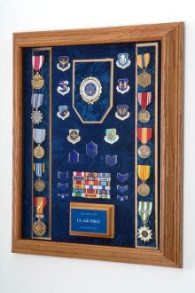 A beautifully crafted military awards display case made of solid oak, featuring an embossed emblem and a luxurious crushed velvet interior.