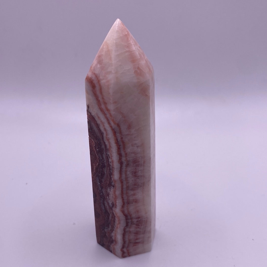 A polished Banded Calcite Point showcasing vibrant pink, white, and red stripes, symbolizing peace and harmony.