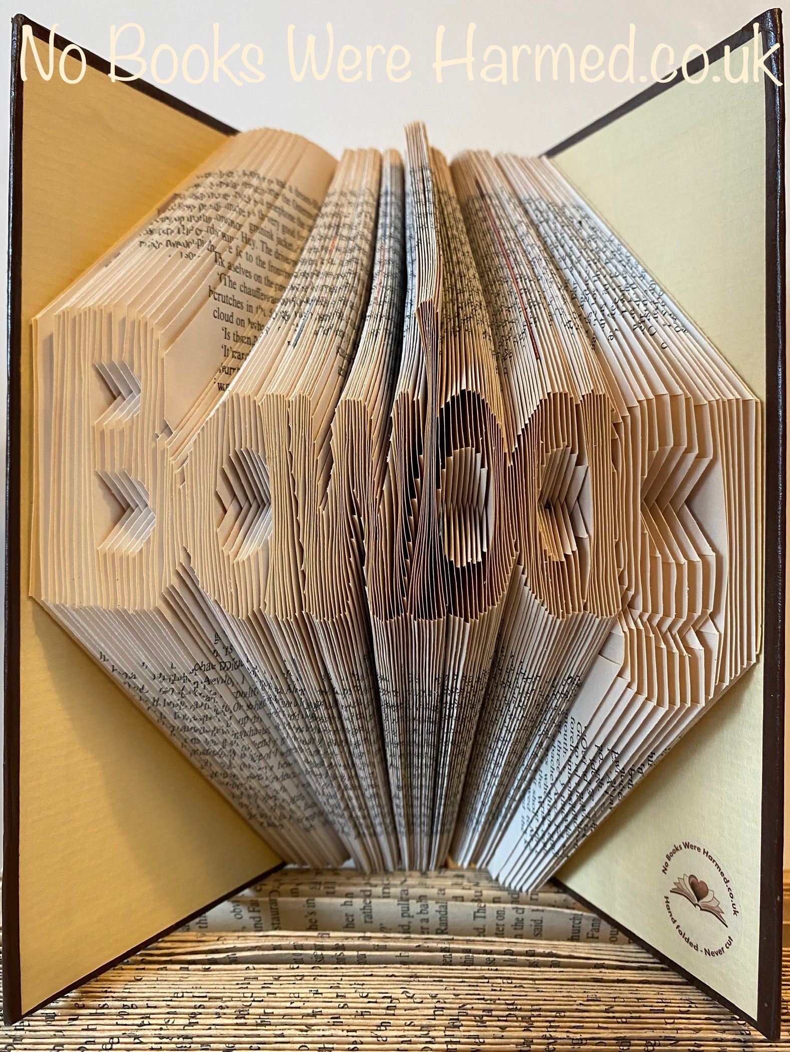 A unique hand-folded book art piece shaped like a bawbag, crafted from vintage book pages, showcasing intricate folds and a playful design.
