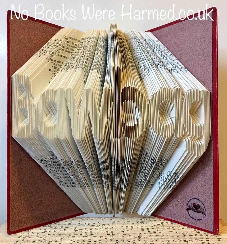 A unique hand-folded book art piece shaped like a bawbag, crafted from vintage book pages, showcasing intricate folds and a playful design.