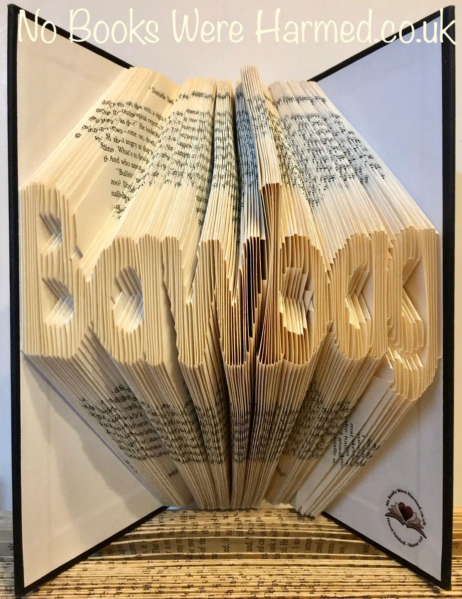 A unique hand-folded book art piece shaped like a bawbag, crafted from vintage book pages, showcasing intricate folds and a playful design.
