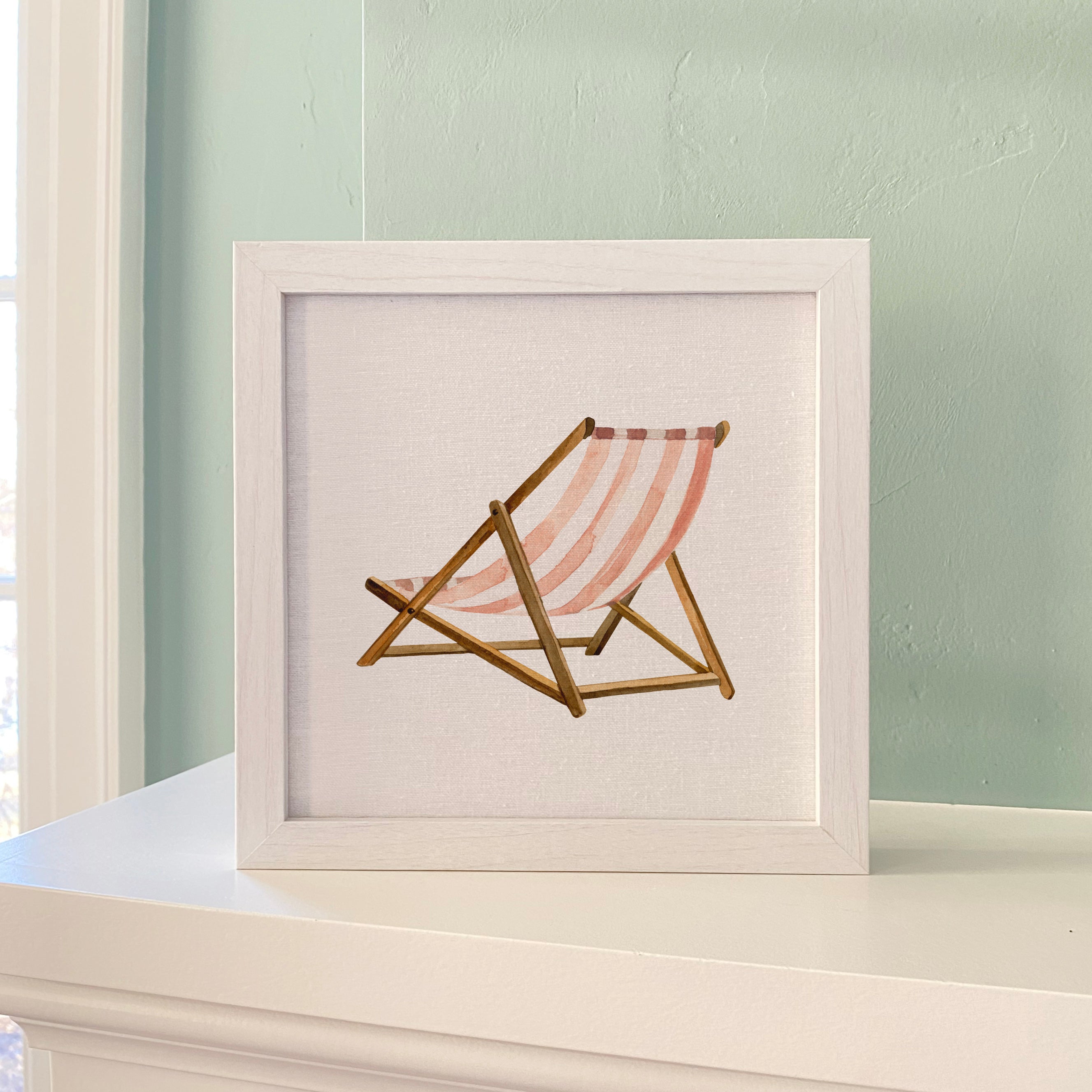 A stylish Beach Chair Framed Sign with a wood frame, featuring a linen-look background and eco-friendly printing, available in walnut and white-washed finishes.