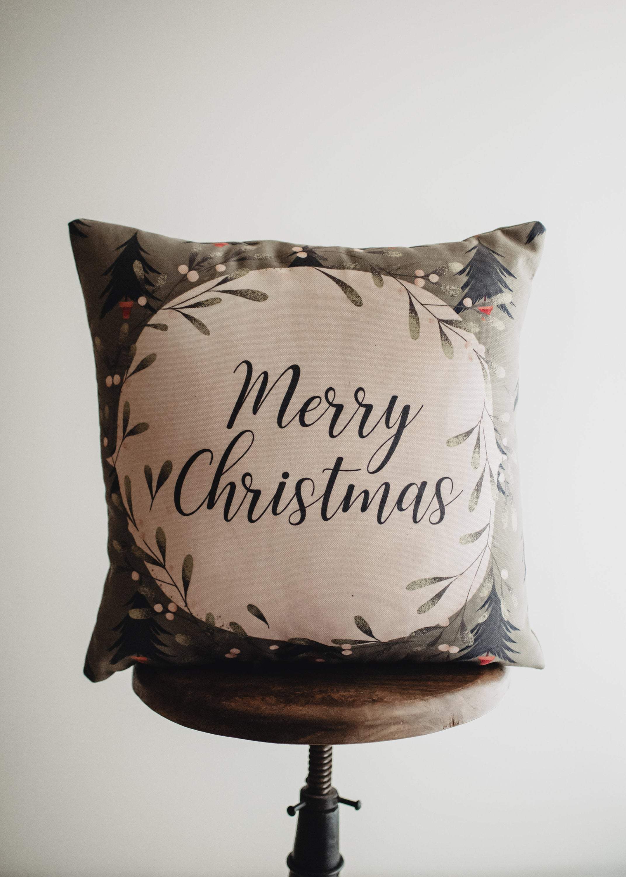 Beige Merry Christmas Throw Pillow Cover featuring a white circle with 'Merry Christmas' text, green wreath, and blue trees on a gray-green background.