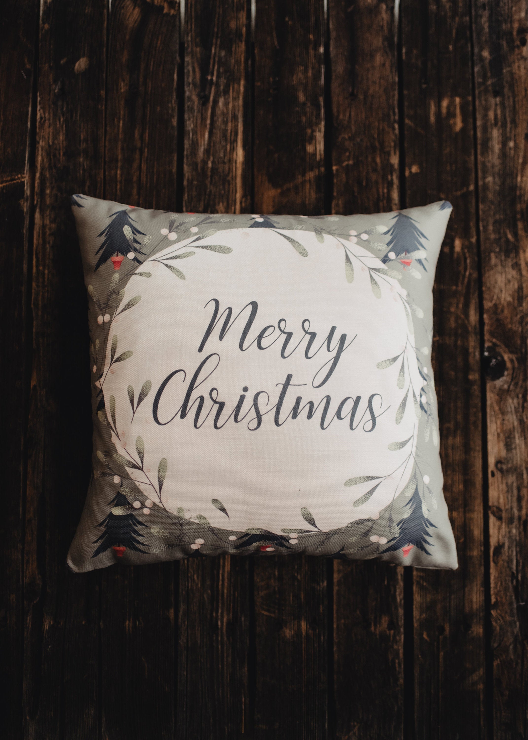 Beige Merry Christmas Throw Pillow Cover featuring a white circle with 'Merry Christmas' text, green wreath, and blue trees on a gray-green background.